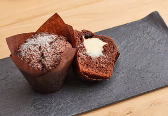 Chocolate muffins filled with cream cheese on a wooden table