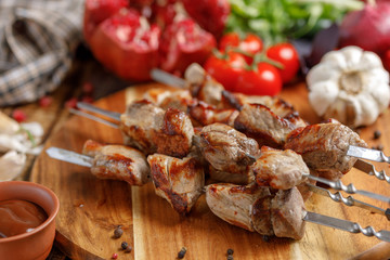 Juicy appetizing shish kebabs cooked on an open fire. Still life with textiles on a wooden background.