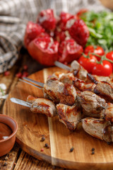 Meat on skewers cooked on an open fire. Still life with textiles on a wooden background.