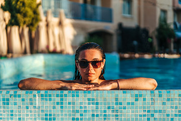 Pretty brunette girl relaxing at the swimming pool