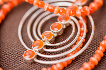 Serdolik (carnelian) stone necklace laying on natural brown linen tablecloth. Yashma, orange jasper, onyx gemstones around. Healing, powerful energy for crystal therapy treatments. Esoteric background