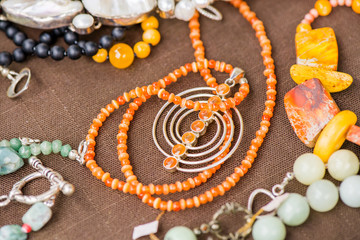 Serdolik (carnelian) stone necklace laying on natural brown linen tablecloth. Yashma, orange jasper, onyx gemstones around. Healing, powerful energy for crystal therapy treatments. Esoteric background