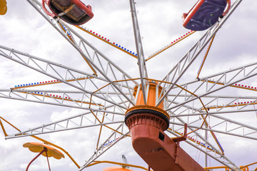 Colorful roller coaster seats at amusement park. People having fun in carousel. Wheel is spinning...