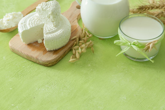 Shavuot concept - dairy products and wheat on green wood background