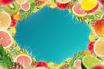 Frame of tropical fruits with water splash on blue background, empty space in the middle