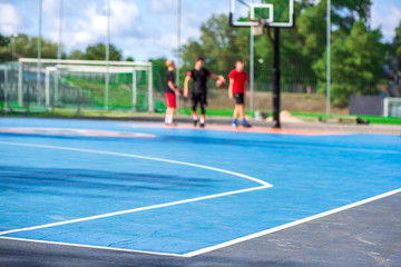 Abstract, blurry background of boys playing basketball in outdoor basketball court in park