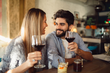 Cheers! Happy smiling couple drinking wine at their date at the restaurant