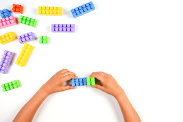 Kid hands with colorful plastic construction blocks on white background
