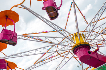 Colorful roller coaster seats at amusement park. People having fun in carousel. Wheel is spinning...