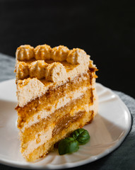 Slice of layered honey cake in a plate on wooden table