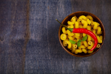 Pasta in a wooden bowl with hot chili and basil