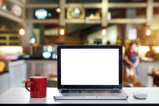 
Front view of cup and laptop on table in office and background  in the coffee shop and restaurant
