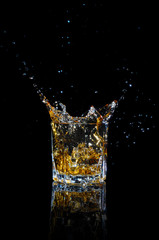Whiskey with splash on black background.