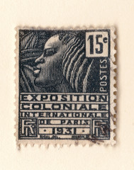 An old black french postage stamp with an illustration of a stylized african woman commemorating a colonial exhibition in 1931 - obrazy, fototapety, plakaty