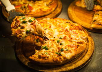 pickup pizza by pizza lap,eating hawaiian pizza,pizza put on wooden plate with warm light,peanut pizza lay on wooden plate