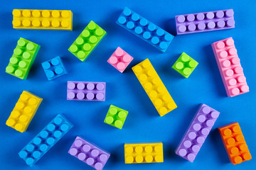 Colorful plastic construction blocks pattern on blue background