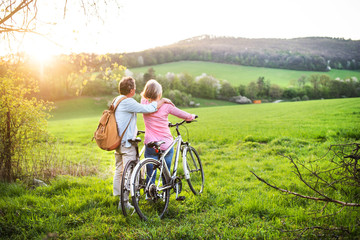 Fototapeta premium Beautiful senior couple with bicycles outside in spring nature.