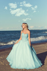 Fototapeta na wymiar woman in blue tulle dress enjoying sun on beach