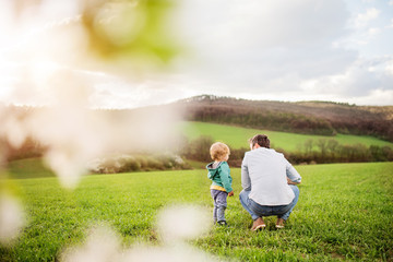 A father with his toddler son outside in spring nature.