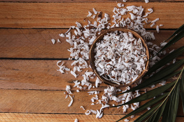 fresh natural coconut shavings, palm leaves, half coconut on the background of wood. 