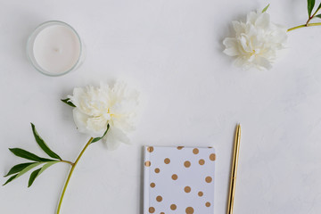 Flat lay desk with white peonies, notebook and accessories