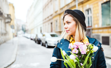 Young woman with flowers in sunny spring town.