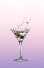 A splash of martini in a cocktail glass with olives.