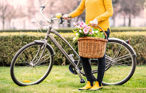 Young woman with bicycle standing outside in sunny spring.