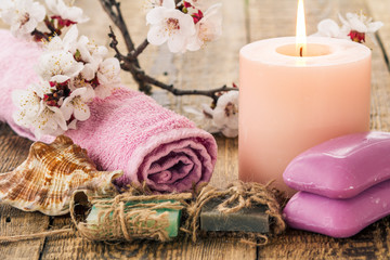 Obraz na płótnie Canvas Soap with towel for bathroom procedures, sea shell and burning candle with flowering branch of apricot tree