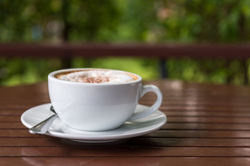 Cappuccino cup on wooden table with bokeh view