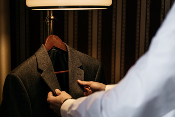A man takes off his coat jacket, cropped image