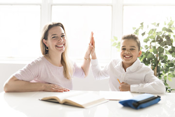 mother help Black boy doing homework at home