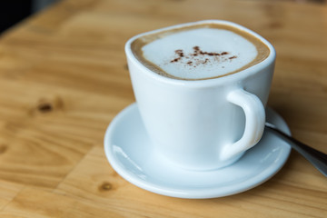Hot cappuccino cup on wooden table top view