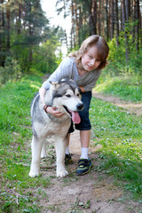 boy with his dog malamute on a walk in the forest