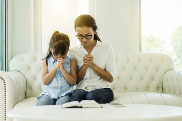 woman and little girl  praying on holy bible