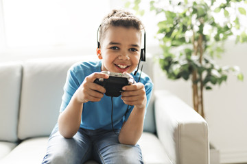 black boy play video game on sofa with headset