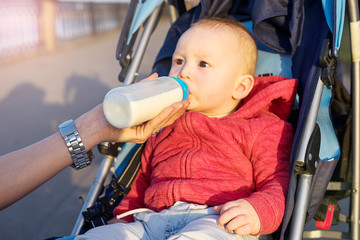 Baby in the stroller drinks milk