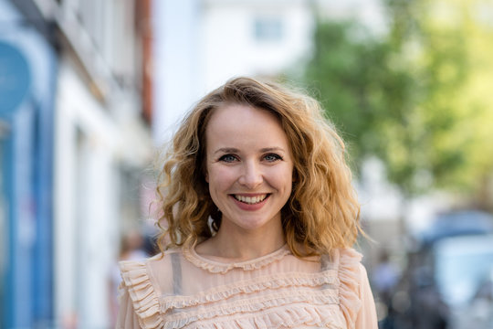 Adult Female Smiling To Camera Outdoors In City