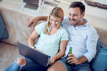 Young couple sitting in the living room and using laptop.