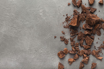 Crushed chocolate pieces on gray background, top view
