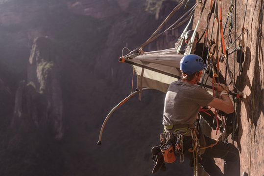 Two rock climbers attaching portaledge to rock, Liming, Yunnan Province, China
