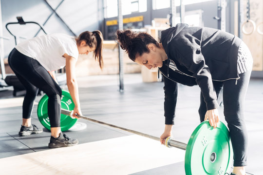 Women preparing weights equipment in gym