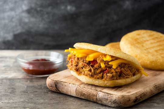 Arepa with shredded beef and cheese on wooden background. Venezuelan typical food