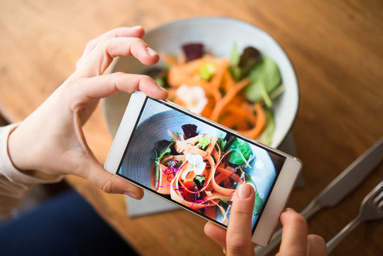 Woman taking photo of vegan meal