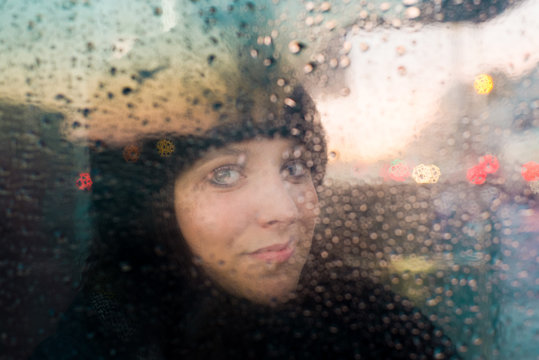 Woman looking out of rain splashed window