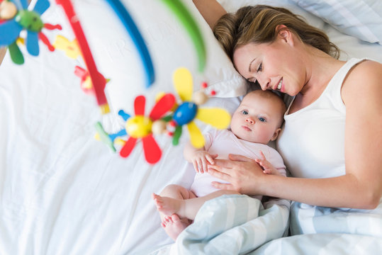 Mother and baby in bed, looking at crib carousel