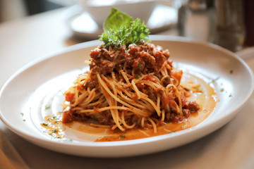 spaghetti Bolognese with minced beef and tomato sauce garnished with parmesan cheese and basil , Italian food