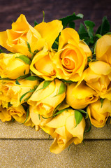 Yellow roses with gift box on wooden background.