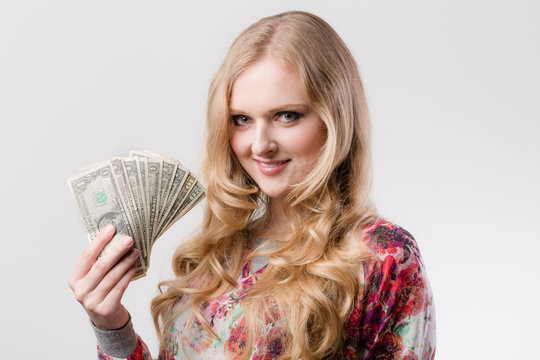 Junge Frau freut sich und h&auml;lt Dollarscheine in der Hand