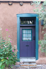 Fototapeta na wymiar purple door with hollyhocks santa fe nm